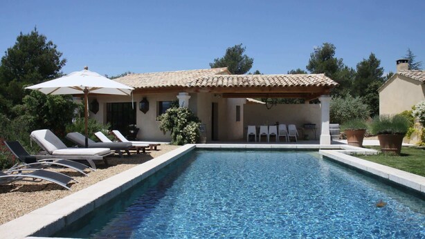 A swimming pool with lounge chairs and a pergola, surrounded by greenery. - La Maison des Restanques (Cabrières-d'Avignon)