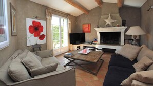 A living room with a fireplace, a television, and a coffee table. - La Maison des Restanques (Cabrières-d'Avignon)
