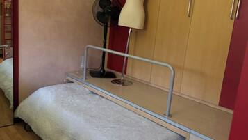 Una camera da letto con un letto, un armadio, una ventola e una lampada.