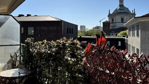 Eine Dachterrasse mit Blick auf ein historisches Gebäude, einem Tisch mit Stühlen und verschiedenen Pflanzen.