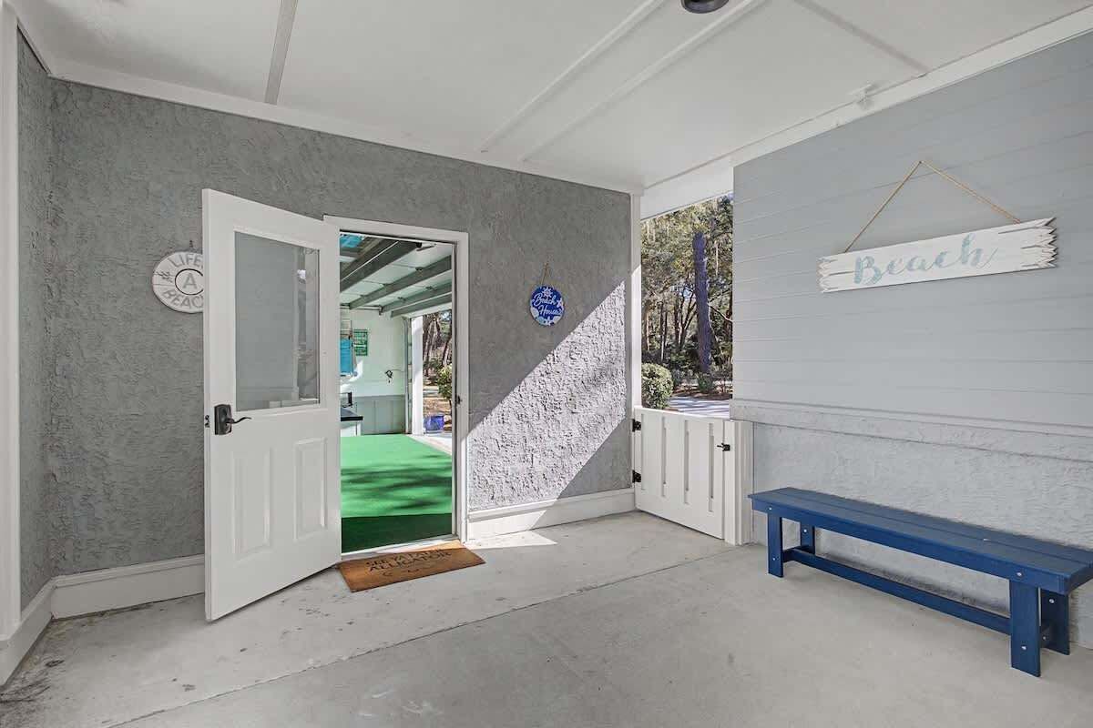 A room with a white door, a blue bench, and a wall sign that says 'Beach'.