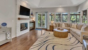 A modern living room with a fireplace, a television, a sofa, and a ceiling fan. - Private Pool, Lagoon View, & Walk to Beach! (Hilton Head Island)