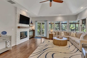 A modern living room with a fireplace, a television, a sofa, and a ceiling fan. - Private Pool, Lagoon View, & Walk to Beach! (Hilton Head Island)