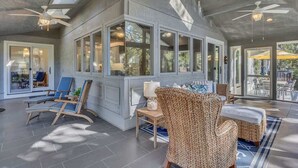 A spacious indoor area with ceiling fans, large windows, and wicker furniture. - Private Pool, Lagoon View, & Walk to Beach! (Hilton Head Island)