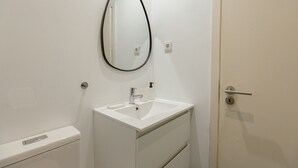A bathroom with a white sink, a mirror, a toilet, and a door. - Downtown Formosa Studio by Vacationy (Porto)