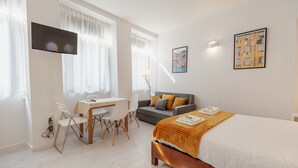 A hotel room with a bed, a desk, a sofa, and a TV. - Downtown Formosa Studio by Vacationy (Porto)