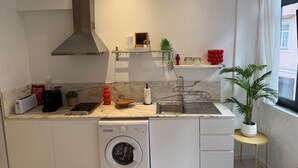 A compact kitchen with a built-in washing machine, a sink, and a window with a view. - Downtown Formosa Studio by Vacationy (Porto)