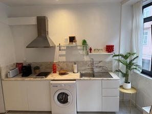 Eine kompakte Küche mit Einbauwaschmaschine, Spüle und Fenster mit Blick.