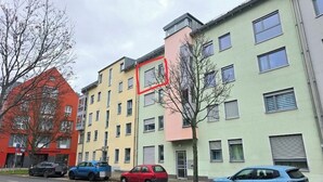 A row of multi-story residential buildings with a variety of colors, parked cars, and a tree in the foreground. - Furnished apartment near Plauen's old market square with sunny balcony (Plauen)