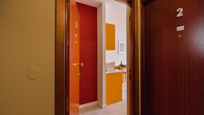 A hallway with a red door, a number '2' sign, and a small desk with a chair. - Colorful Studio 1 Municipal Pool by Vacationy (Porto)