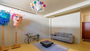A living room with a gray sofa, a black coffee table, a bicycle, and two colorful sculptures. - Colorful Studio 3 Municipal Pool by Vacationy (Porto)