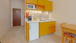 A compact kitchen with yellow cabinets, a microwave, a coffee machine, and a sink. - Colorful Studio 3 Municipal Pool by Vacationy (Porto)