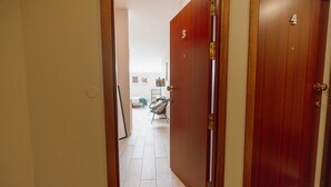 A hallway with doors numbered 3 and 4, leading to a room with a chair and a small table. - Colorful Studio 3 Municipal Pool by Vacationy (Porto)