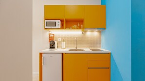 Una cucina compatta con forno a microonde, macchina del caffè e mini-frigorifero.
