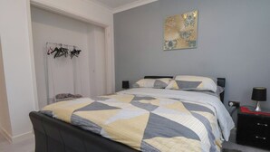 A bedroom with a bed, a bedside table, a lamp, and a wall art piece. - Flat 12 (Wallasey)