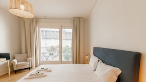 Hotellihuone, jossa on suuri sänky, tuoli, työpöytä ja parveke, jolta on näkymä.