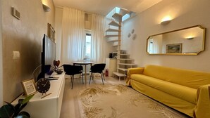 Uma sala de estar moderna com um sofá amarelo, uma escrivaninha branca com um computador, uma escada em espiral e um espelho grande.