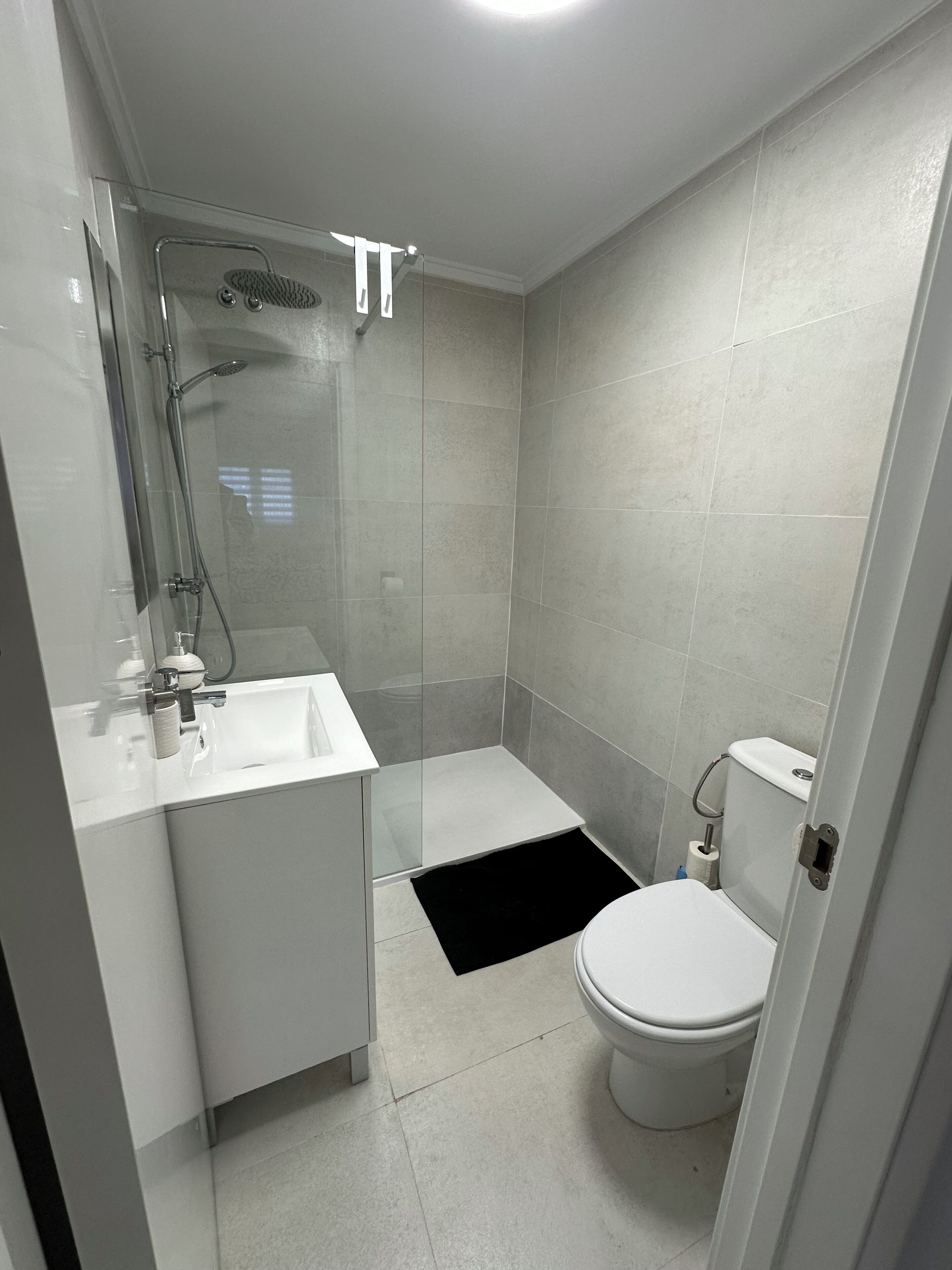 A modern bathroom with a glass shower enclosure, a white sink, and a toilet.