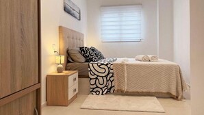 Une chambre à coucher avec un lit, une table de chevet, une lampe et une fenêtre avec des stores.