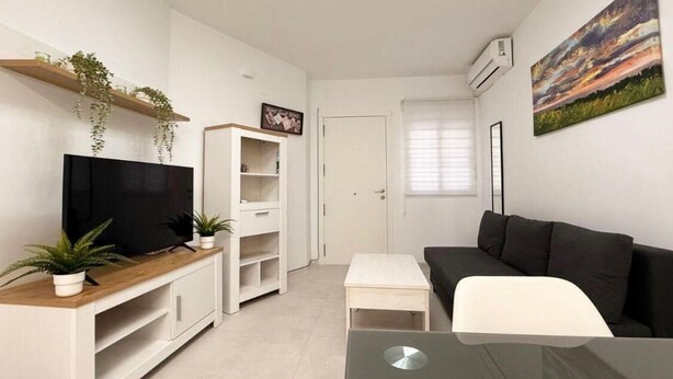 Un salon moderne avec un téléviseur à écran plat, un canapé, une table basse et un tableau accroché au mur.