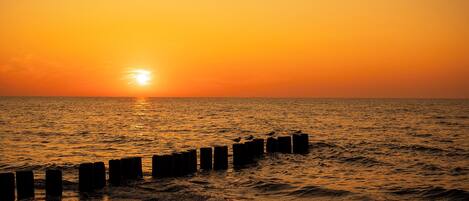 A sunset over the ocean with a wooden pier extending into the water.