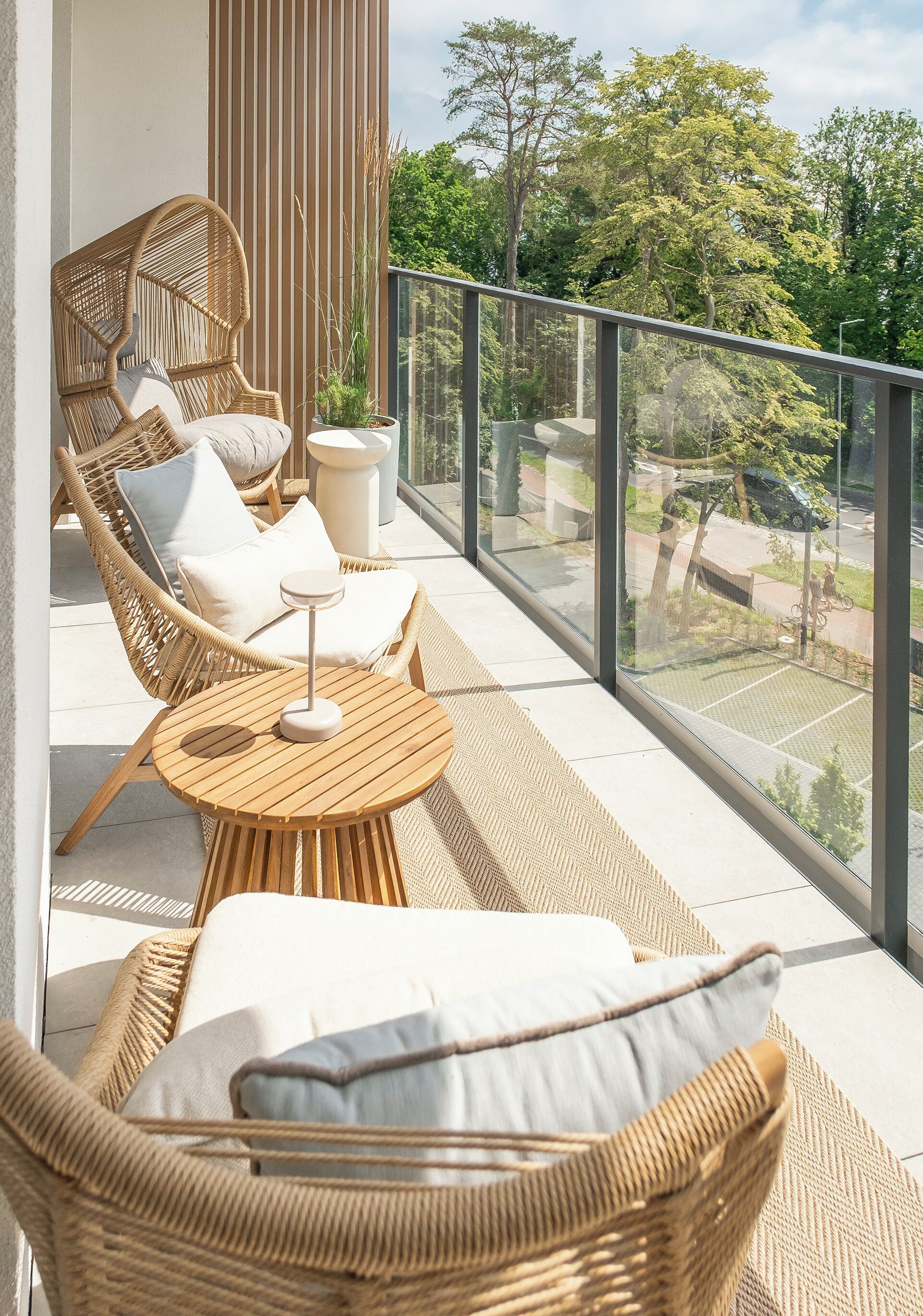 A balcony with wicker furniture, a round table, and a potted plant.