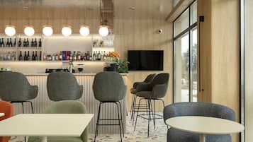 A modern bar area with a wooden bar counter, seating with round tables and chairs, and hanging plants.