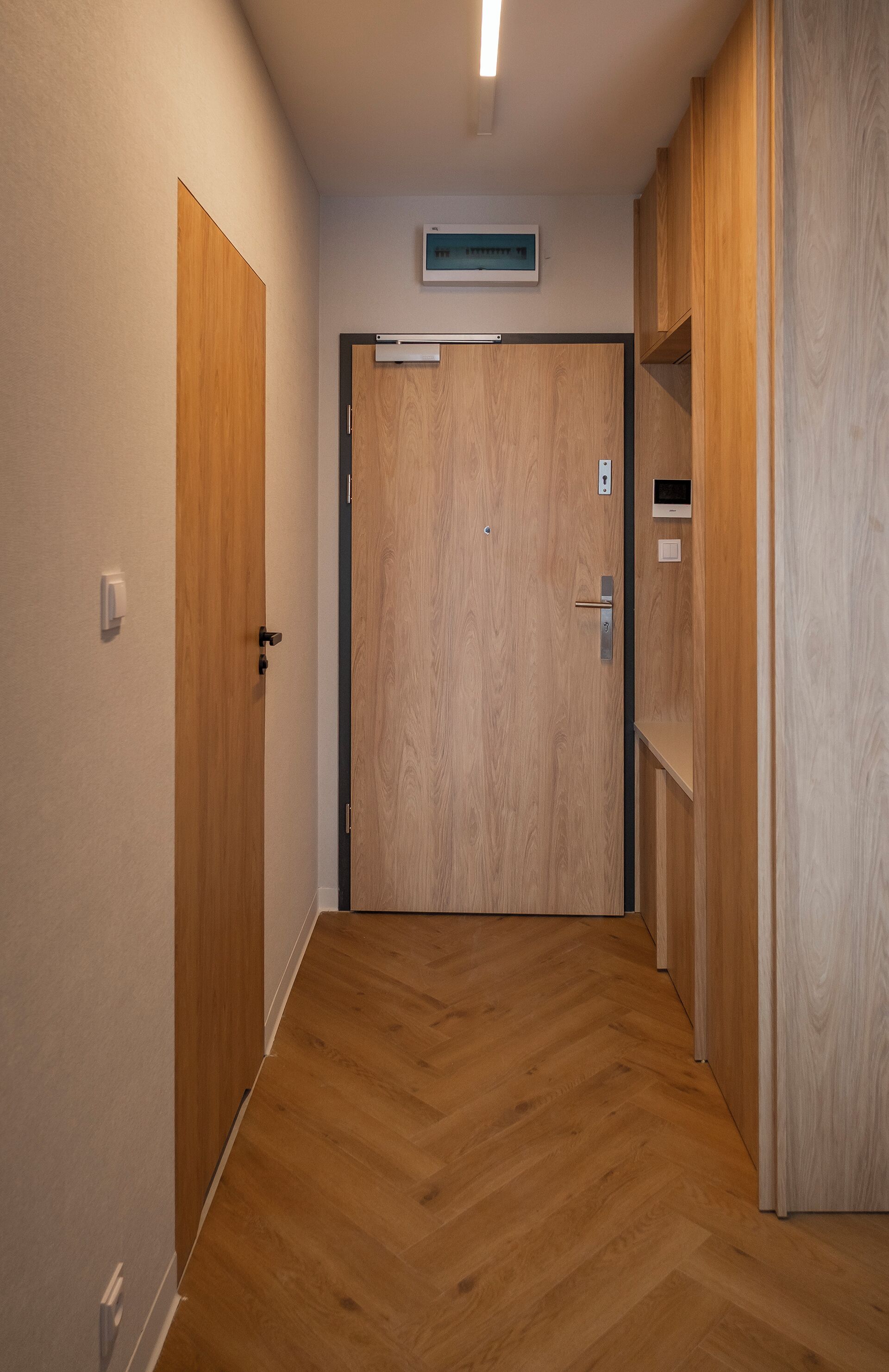 A hallway with wooden doors and a herringbone-patterned floor.