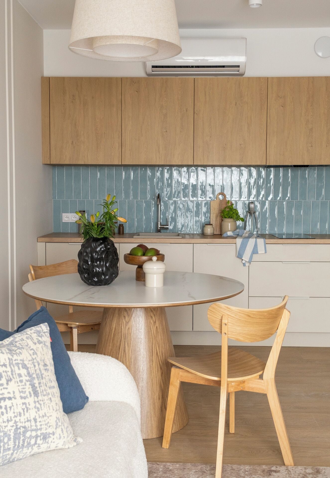 A modern kitchen with wooden cabinets, a round dining table, and a built-in stove.