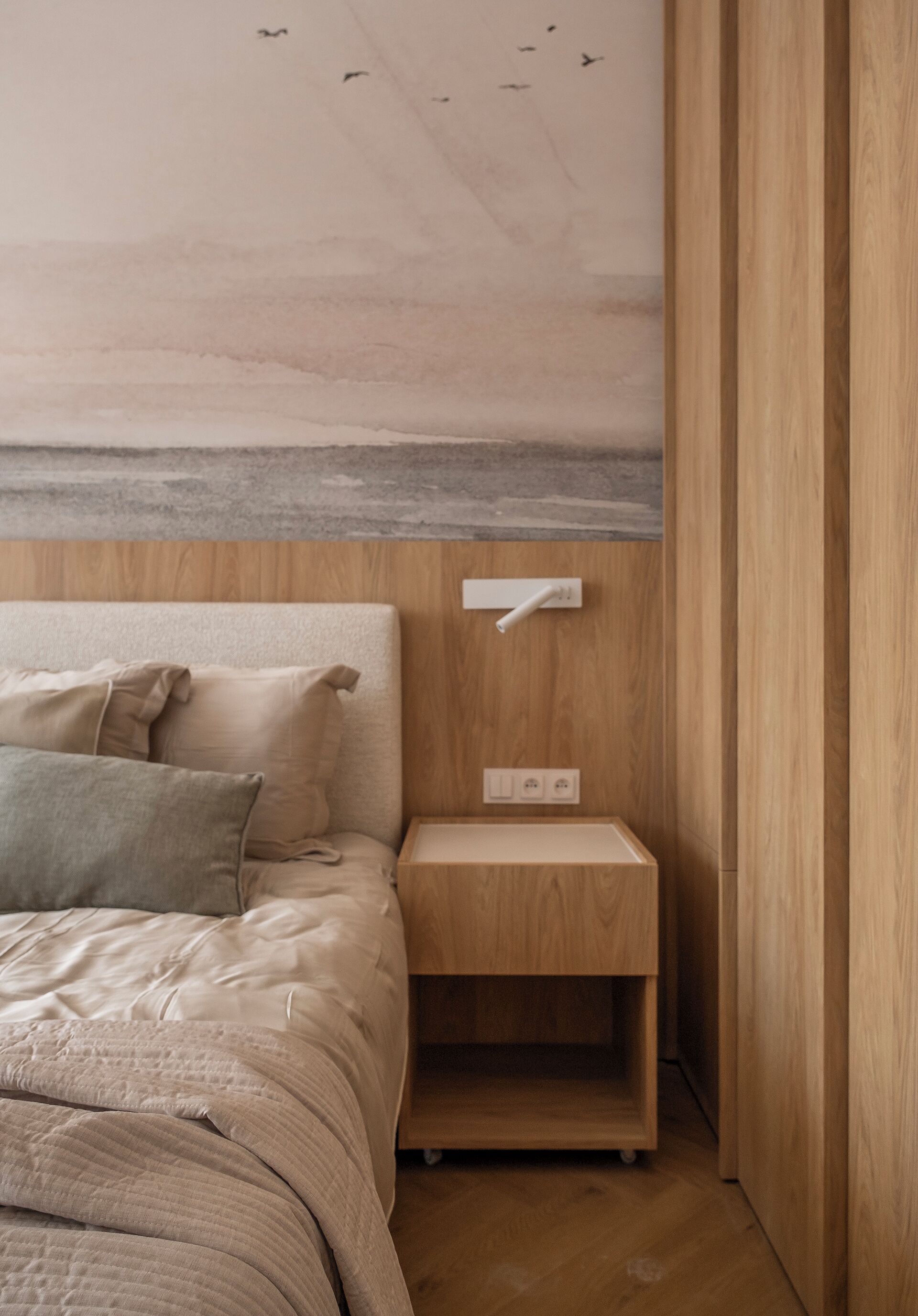 Un dormitorio con cama, mesita de noche y un mural en la pared.