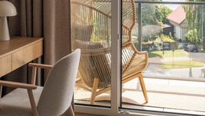 Una habitación con un amplio ventanal corredera que da a un balcón con una silla de mimbre y vistas al mar.