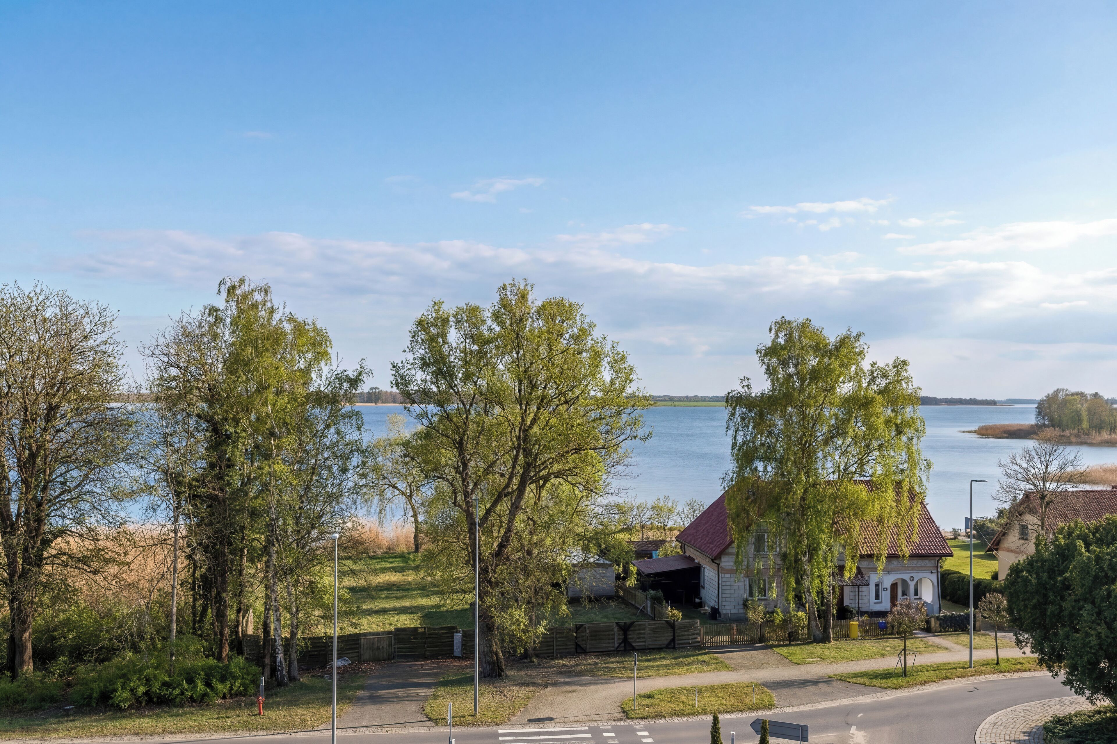 A lakeside property with a house, trees, and a clear view of the water.