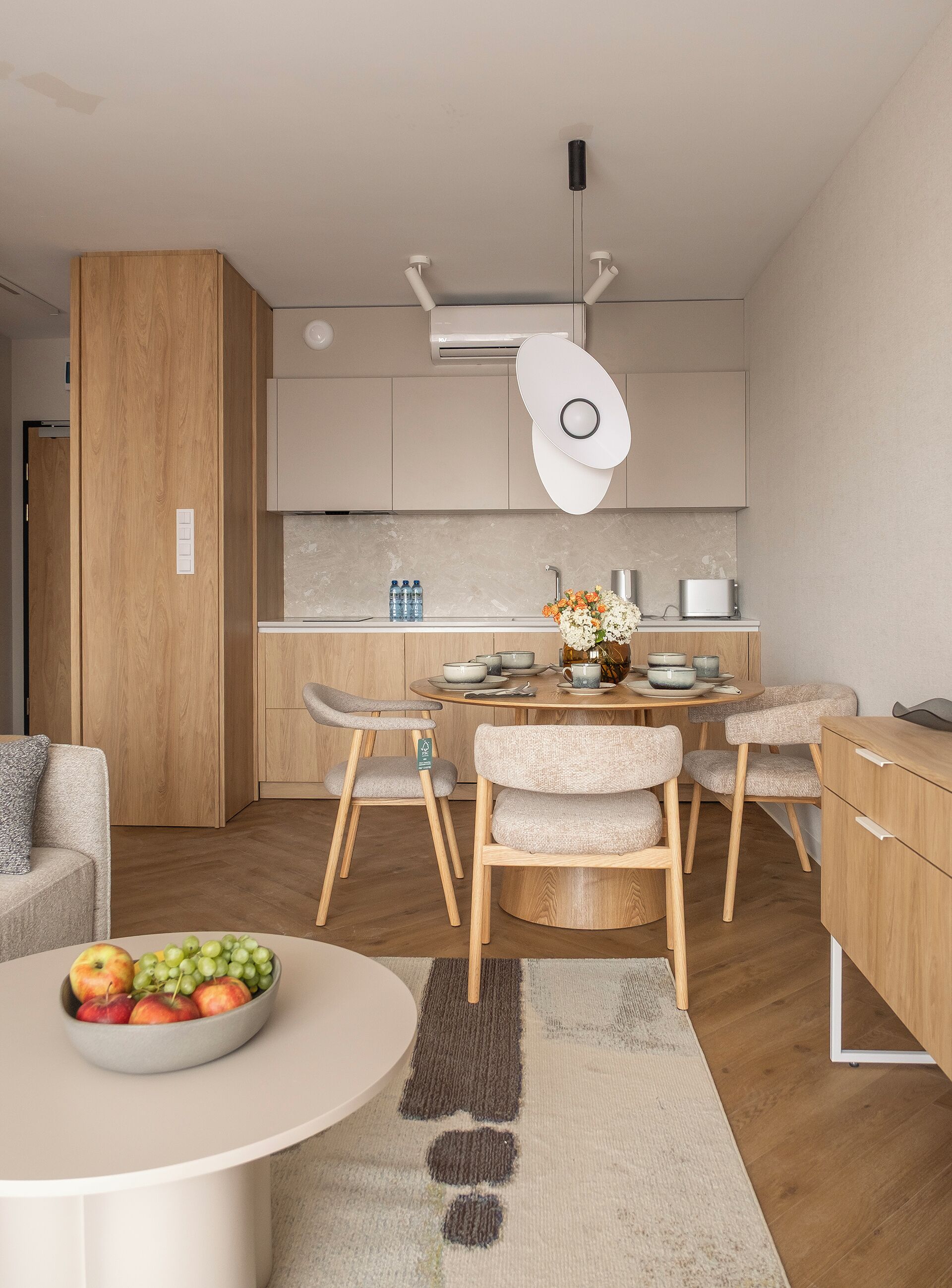 A modern kitchen with wooden cabinets, a central island with seating, and a dining area with a table set for four.