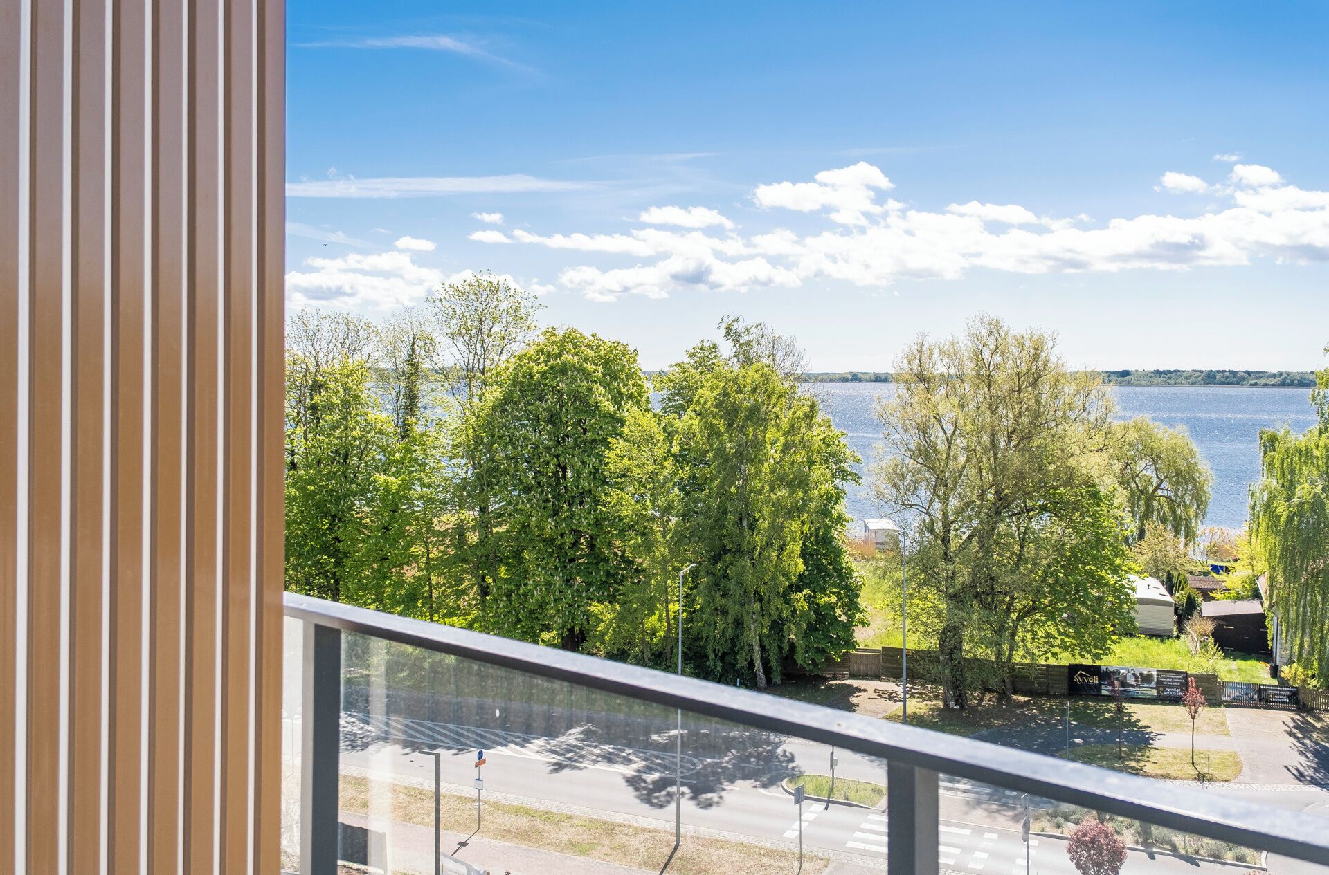 A balcony with a view of a lake, trees, and a distant shoreline.