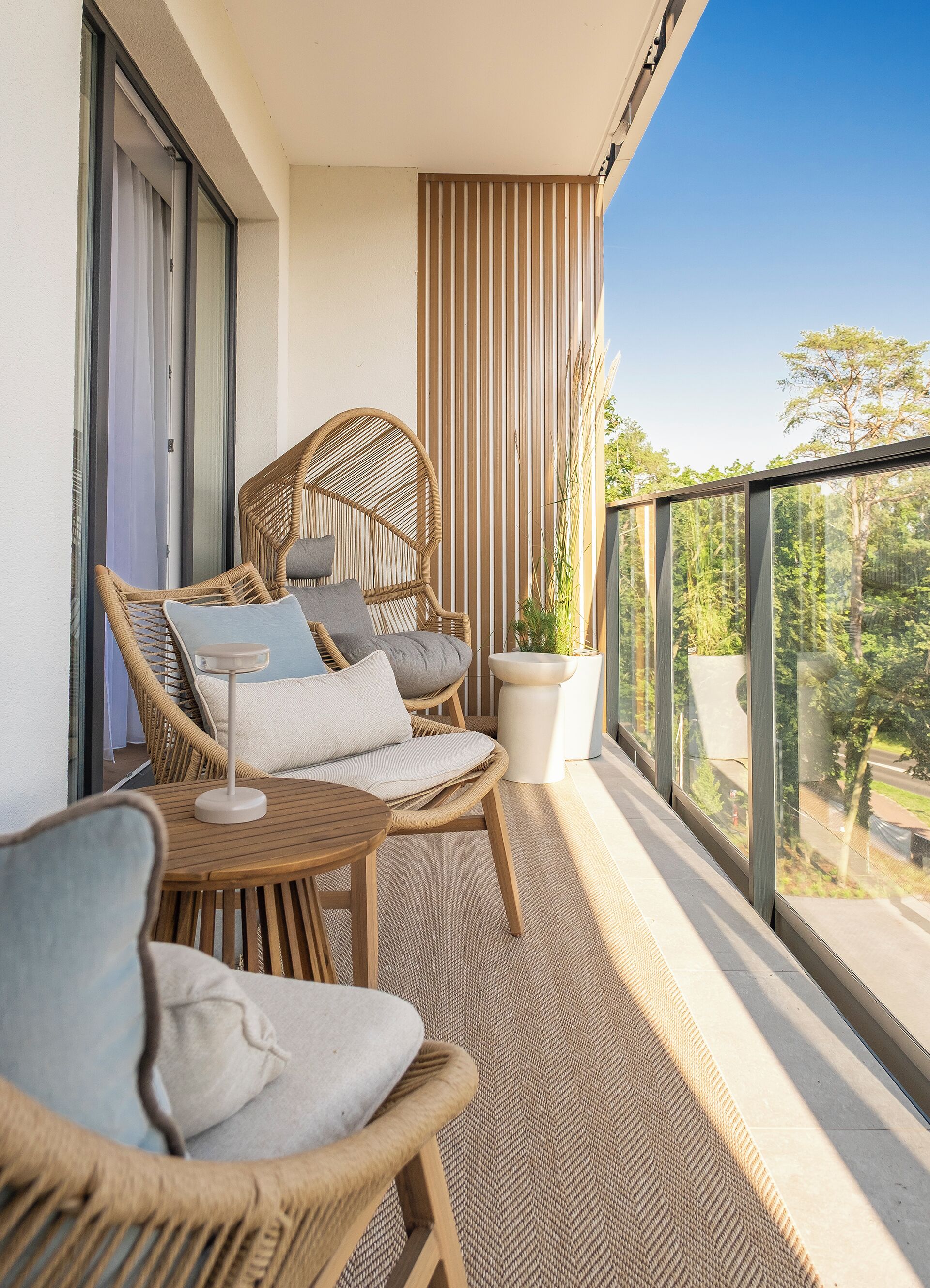 A balcony with wicker furniture, a small table, and a potted plant.