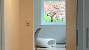 A hallway with wooden flooring, a white wall, and a window with a view of pink flowers. - Modern Feel-Good Apartment in Marbach am Neckar Near Schillerhöhe (Marbach am Neckar)