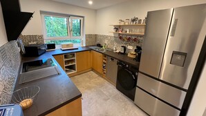A modern kitchen with a built-in washing machine, a stainless steel refrigerator, and a window providing natural light. - Modern Feel-Good Apartment in Marbach am Neckar Near Schillerhöhe (Marbach am Neckar)