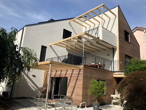 Un immeuble moderne à plusieurs étages, doté d’un balcon, d’un espace extérieur aménagé et d’une plante en pot.