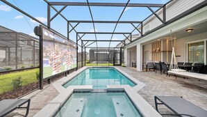 En swimmingpool med et overdækket område, udendørs siddepladser og et stort skærmbillede, der viser en sportsbegivenhed.