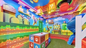 Et farverigt legeområde med Mario og Luigi figurer, en grøn dør og en rutchebane.