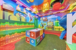 Ein bunter Spielbereich mit Figuren von Mario und Luigi, einer grünen Tür und einer Rutsche.