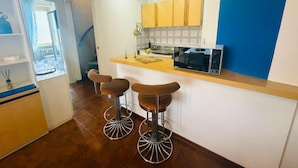 A modern kitchen with a bar area, wooden cabinets, and a microwave. - Attico del Sole con Vista Mare e Terrazza (Marina di Andora)