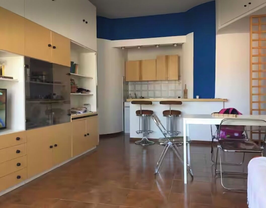 A kitchen with wooden cabinets, a white countertop, and two bar stools.