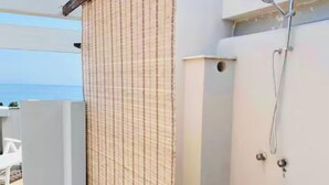 A small, enclosed outdoor shower area with a tiled floor, a white wall, and a metal showerhead. - Attico del Sole con Vista Mare e Terrazza (Marina di Andora)