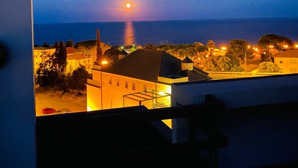 A framed view of a coastal town at dusk with a prominent building and a sunset over the water. - Attico del Sole con Vista Mare e Terrazza (Marina di Andora)