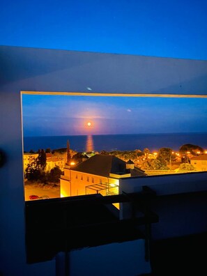 A framed view of a coastal town at dusk with a prominent building and a sunset over the water. - Attico del Sole con Vista Mare e Terrazza (Marina di Andora)