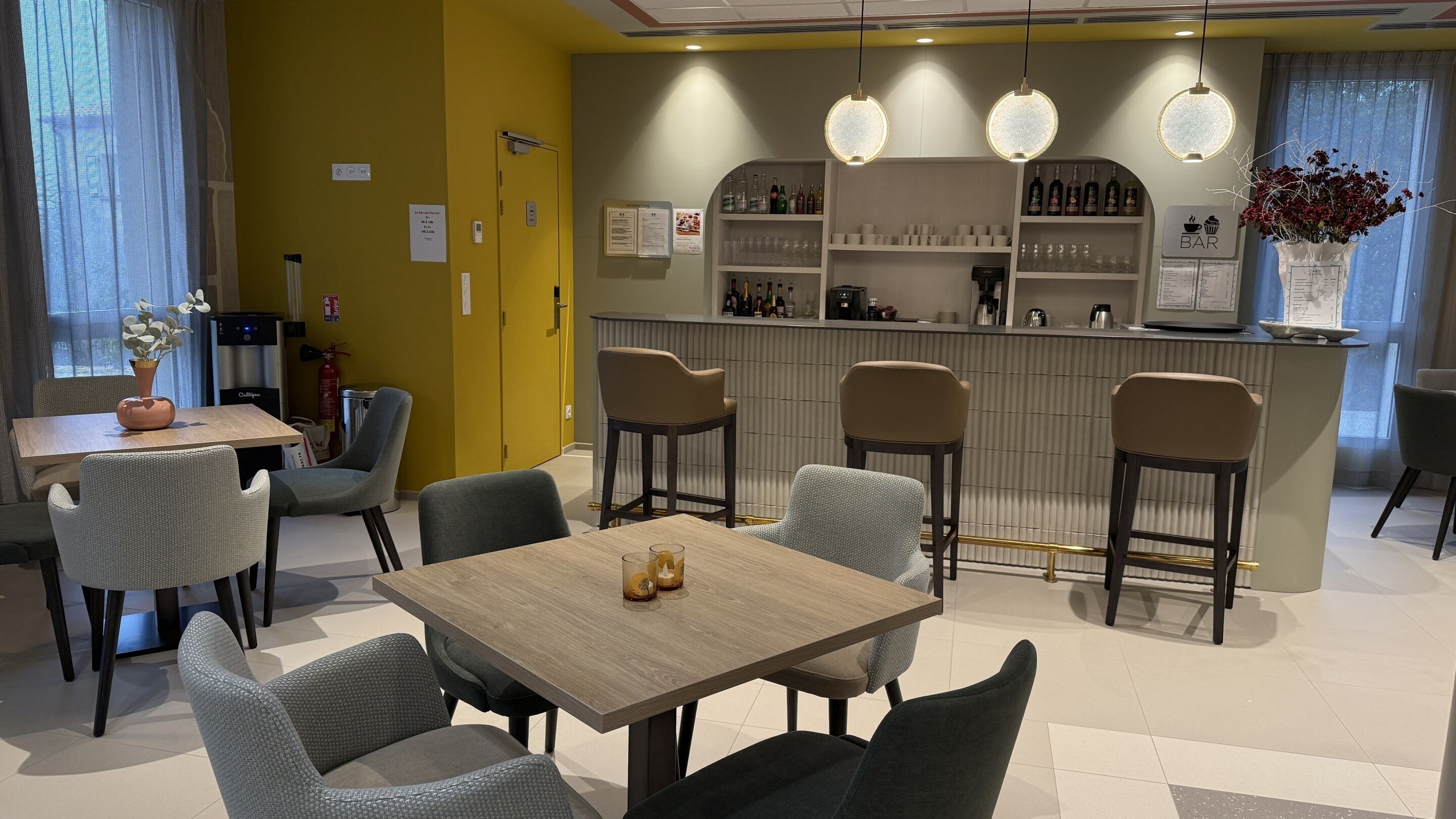 A restaurant with a bar area, seating arrangements, and a counter with various bottles and glasses.