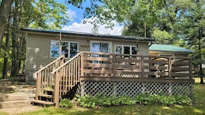 A small cabin with a wooden deck and a staircase leading to the entrance. - Cozy 2 bedroom cottage on lake! (Mountain)