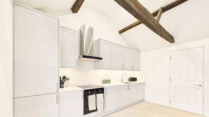 A modern kitchen with white cabinetry, a stainless steel range hood, and a built-in oven. - *NEW* Artisan Apartment | Modern | Spacious (Gloucestershire)