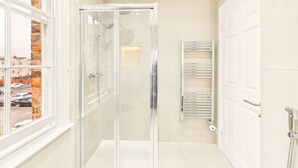 A modern bathroom with a glass shower enclosure, a towel rack, and a white door. - *NEW* Artisan Apartment | Modern | Spacious (Gloucestershire)